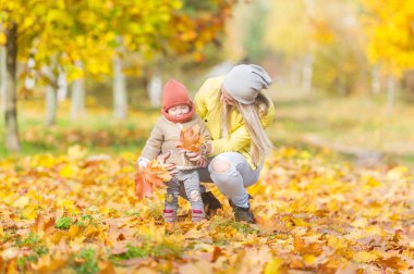 Mutlu anne ve küçük kızı eğlenceli birlikte sonbahar parkta oynarken. Yatay dikey