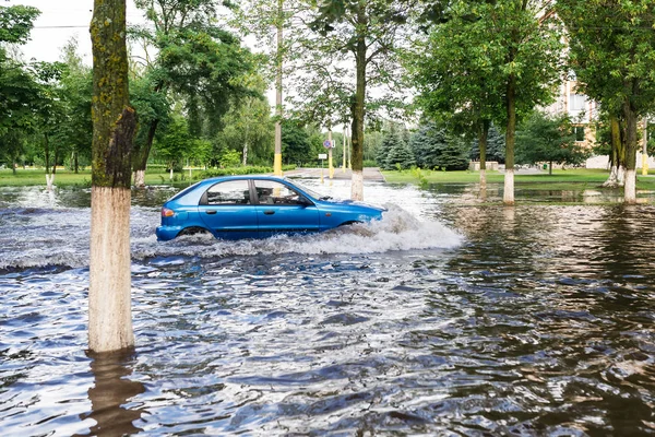 The car driving on a flooded road during a flood caused by heavy rain.