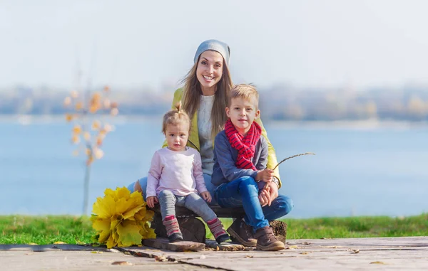 Charming Mother Small Children Sits River Bank Autumn Park Horizontal — Stock Photo, Image