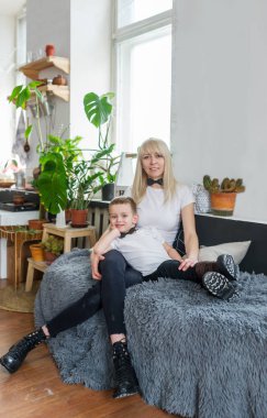 Genç Anne ve oğlu birlikte evde gülmek. Onlar bir aydınlık oturma odasında kanepede hafta sonu birlikte oturuyorlar.