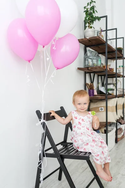 金发碧眼的小女孩 穿着漂亮的连衣裙 坐在黑色的椅子上 粉红色的气球 — 图库照片