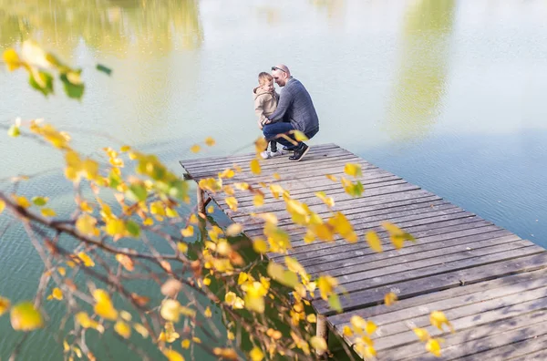 父亲和她的小儿子在温暖的秋日的木码头玩耍 — 图库照片