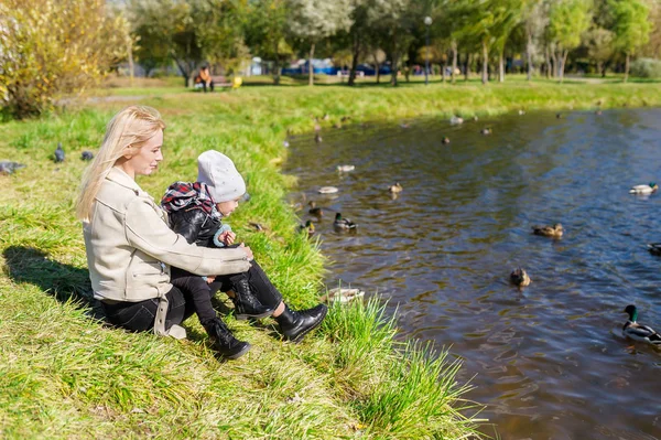 Matka Córką Siedząc Trawie Patrząc Jezioro Pływające Kaczki — Zdjęcie stockowe