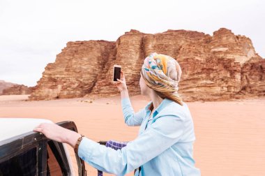 Kadın turist Ürdün çöllerin üstünde hareket eden telefon video veya fotoğraf vuruyor. Gezgin kavramı. Arkadan görünüm