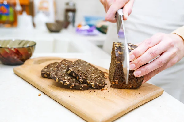 Aşçının kesim çavdar ekmeği ile tohumlar ahşap masa üzerinde eller. Portre fotoğraf