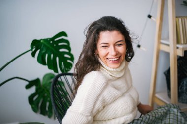 Güzel genç gülümseyen esmer beyaz kazaklı. 