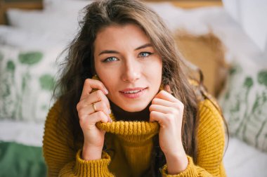 Sıcak kazaklı evde kameraya gülümseyen güzel kadın