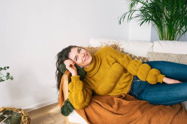 Kot pantolon ve kazak kanepede yatan genç esmer güzel. 