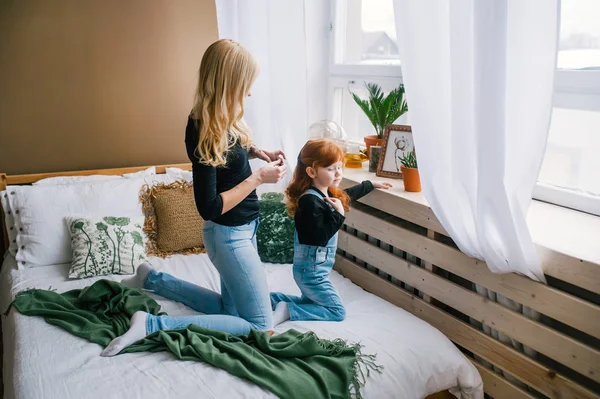 Обережна мати чистить червону доньку в спальні вранці — стокове фото