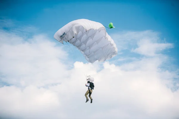 Paracaidista volando en paracaídas blanco en el cielo azul claro en un día soleado brillante del verano. Estilo de vida activo, aficiones extremas —  Fotos de Stock