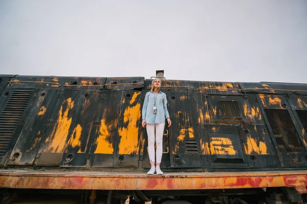 Jovem mulher contra o fundo do carro ferroviário enferrujado jogado — Fotografia de Stock