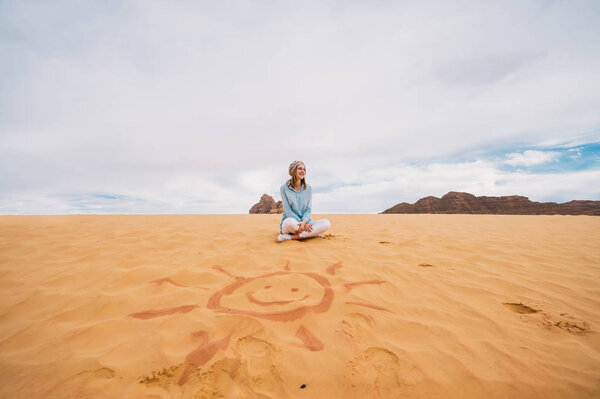 Молодая девушка-путешественница сидит на песчаных дюнах в Вади-Рам, Иордания
.
