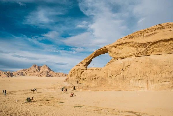 La chica feliz en la roca y el grupo de camellos están en increíble hermoso paisaje en el desierto . — Foto de Stock