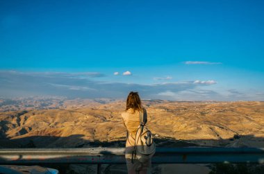 Sırt çantası olan genç kadın dağın tepesinde duruyor.. 