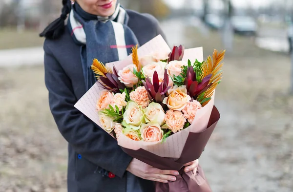 Buquê de rosas em papel que empacota em mãos na mulher . — Fotografia de Stock