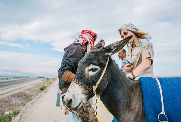 Porträt eines Esels auf einer Straße. Eine Touristin steht in der Nähe. — Stockfoto