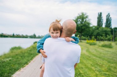 Mutlu ebeveyn parkta açık havada gülümseyen bebek kızı ile oynuyor