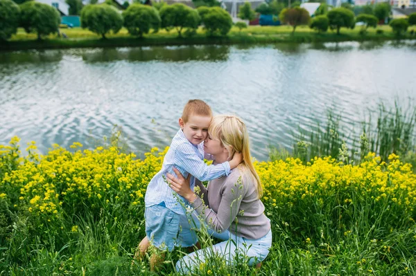 Lovely mother embracing her son in summer city park — Stock Photo, Image