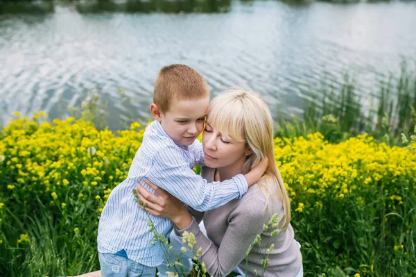 Linda mãe abraçando seu filho no prado de verão — Fotografia de Stock