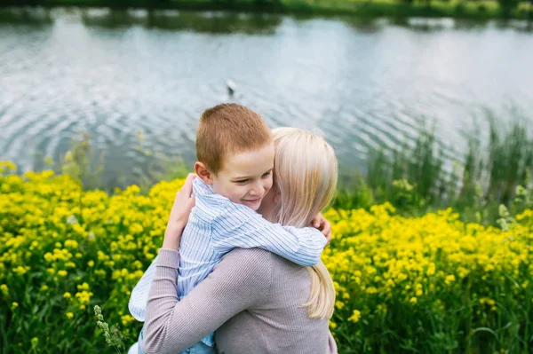 Urocza matka obejmując jej syna w letniej łące — Zdjęcie stockowe