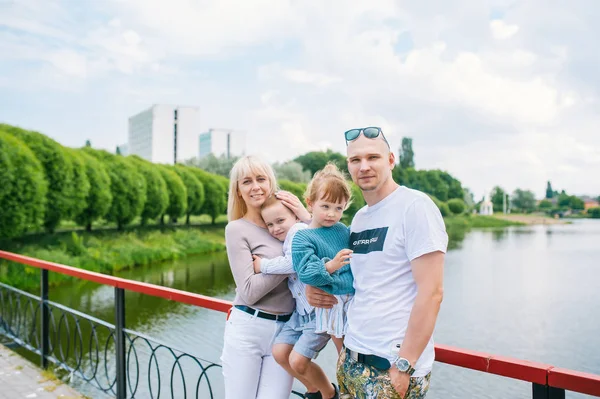 Uma família com uma criança pequena é fotografada em um parque na margem de um rio e em uma ponte . — Fotografia de Stock