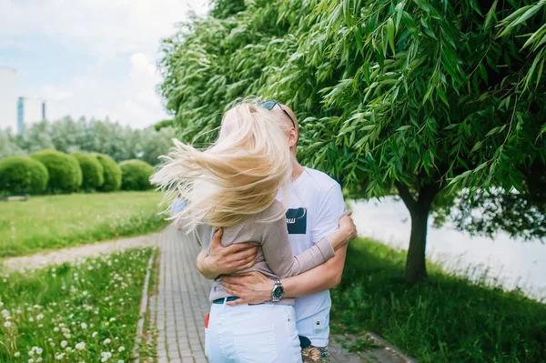 Coppia innamorata si abbracciano e si baciano su uno sfondo di alberi verdi . — Foto Stock