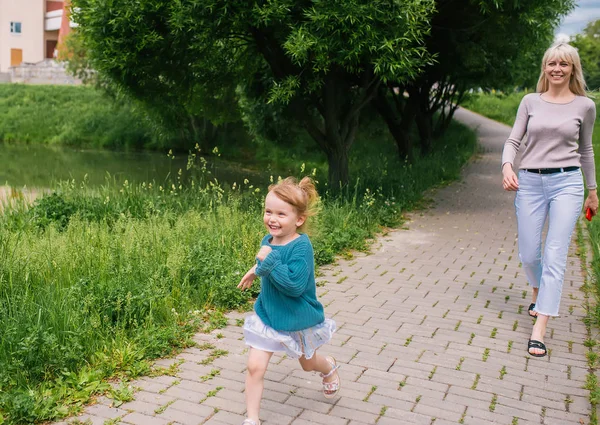 Мать и маленькая дочь прогуливаются в городском парке — стоковое фото