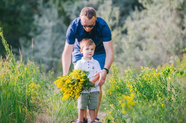 Niño y su padre disfrutando al aire libre en el campo de las flores silvestres —  Fotos de Stock