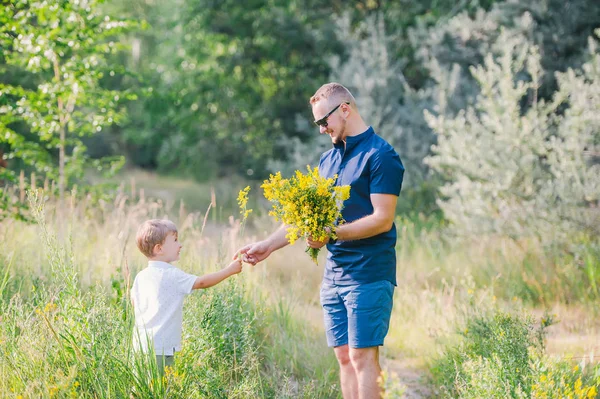 Niño con su padre recoger flores de verano en el prado —  Fotos de Stock