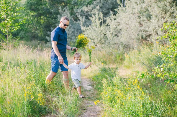 Niño con su padre recoger flores de verano en el prado para la madre —  Fotos de Stock