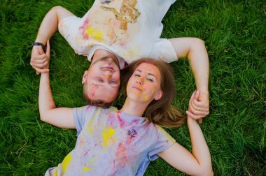 Parkta çimenler üzerinde vücutlarında çok renkli toz ile romantik bir çift. Üstte görüntü.