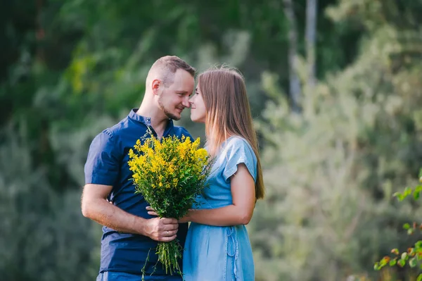 Joven le da a una chica un ramo de flores silvestres . —  Fotos de Stock