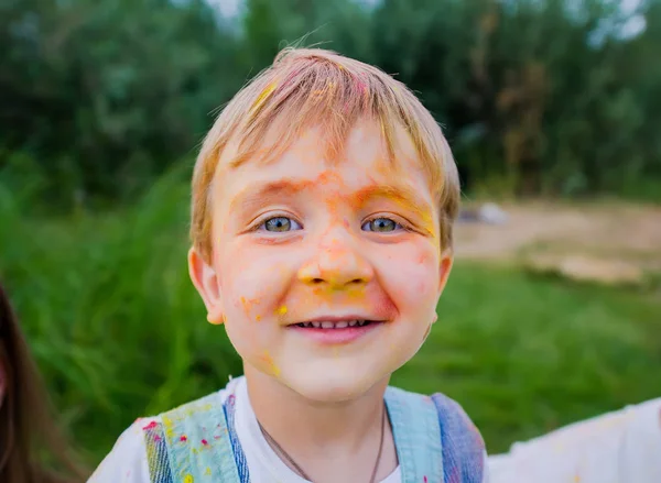 Gezicht van grappige kleine blonde jongen geschilderd in kleurrijke verven. Close-up portret — Stockfoto