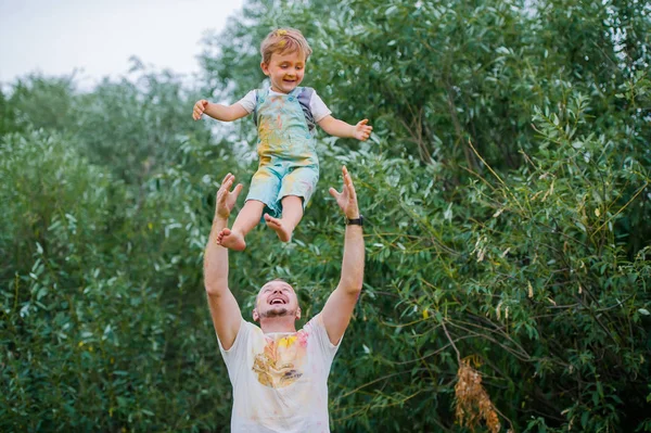 Ευτυχισμένος πατέρας ρίχνει ευτυχισμένο μικρό αγόρι στον αέρα, ενώ παίζοντας υπαίθρια — Φωτογραφία Αρχείου