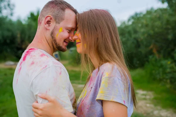 Couple dans des peintures multicolores étreignant dans la prairie d'été. Vue latérale — Photo