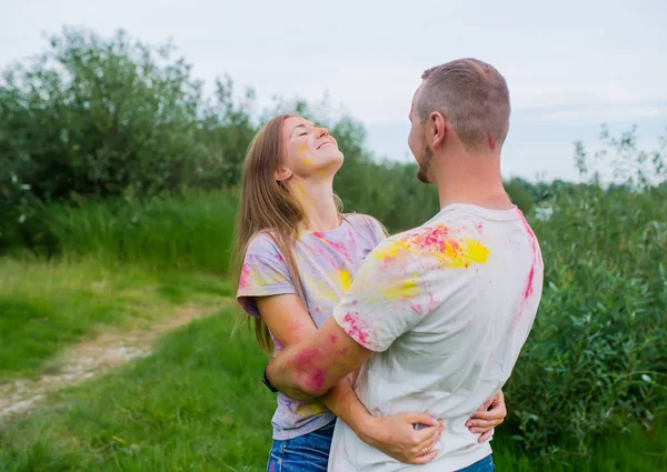 Casal feliz em tintas multicoloridas abraçando no prado de verão . — Fotografia de Stock