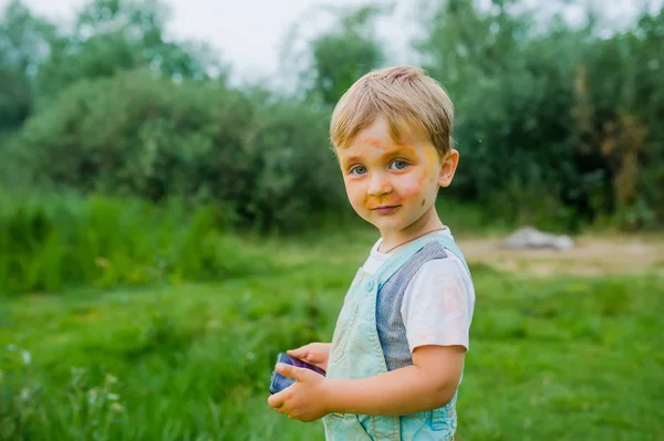 Un petit garçon peint sur de la peinture. Portrait de sale petit garçon avec gadget en plein air — Photo