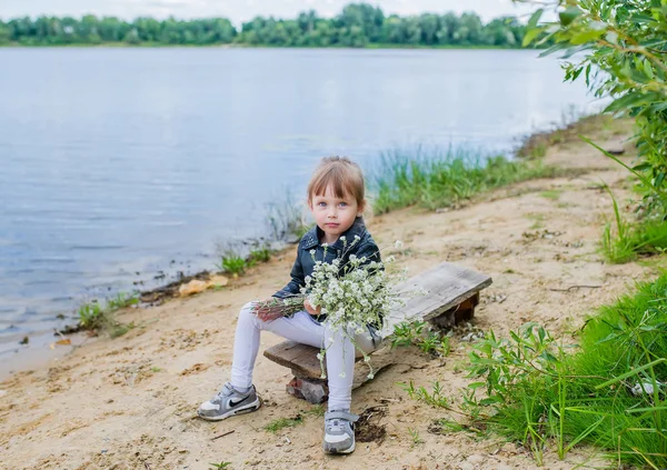 Cute Baby Girl z bukietem kwiatów w pobliżu jeziora — Zdjęcie stockowe