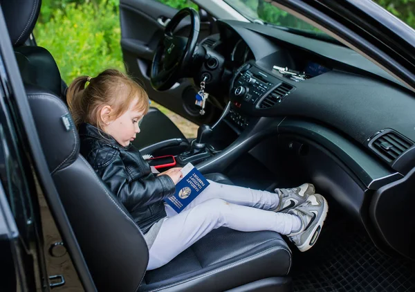Una bambina è seduta sul sedile dell'auto nel passaporto di un cittadino bielorusso . — Foto Stock