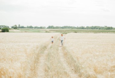 Kardeş ve sevimli kız kardeş uzakta buğday tarlasında çalışan.
