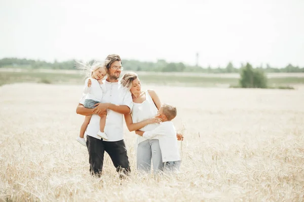 Uma família feliz de quatro se divertindo no campo de trigo no dia ensolarado de verão . — Fotografia de Stock