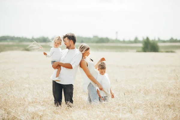 Lovely portrait of a young beautiful family in wheat field on warm and sunny summer day. — Stock Photo, Image
