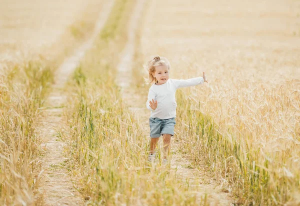 Dziewczynka działa w polu pszenicy w słoneczny dzień — Zdjęcie stockowe