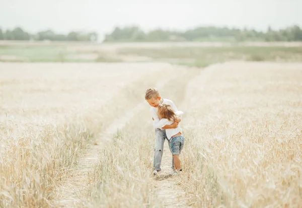 Portrait of brother and little sister together on summer wheat field. — Stock Photo, Image