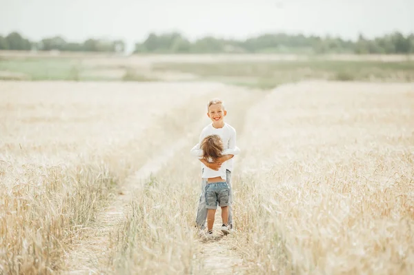 两个可爱的孩子，小女孩和男孩，拥抱在麦田里. — 图库照片