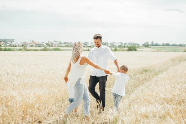 Happy family with children having fun round dancing holding hands together in wheat field. — Stock Photo, Image