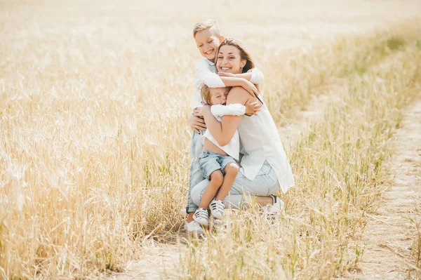 Mom hugging and loving her little kids in wheat field. — Stock Photo, Image