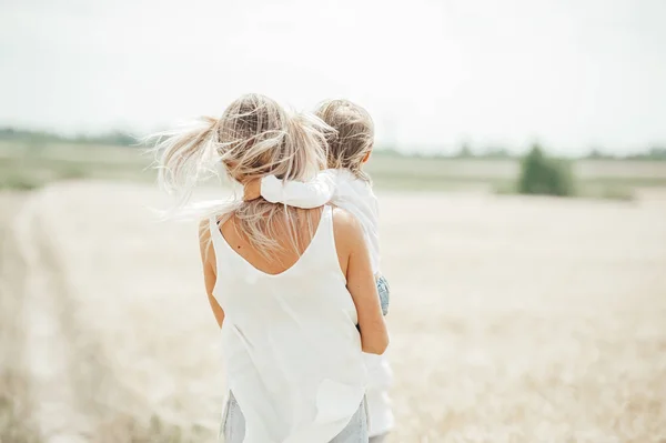 Matka trzyma małą dziewczynę na polu pszenicy. — Zdjęcie stockowe