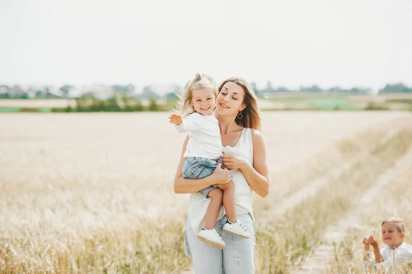 Mamma som håller en liten leende flicka på vete fältet. Mamma med barn utomhus — Stockfoto