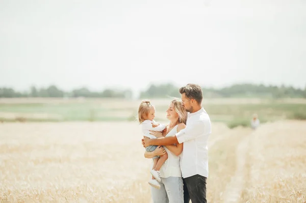 Piękny portret młodej pięknej rodziny w polu pszenicy w ciepłym i słonecznym letnim dniu. — Zdjęcie stockowe